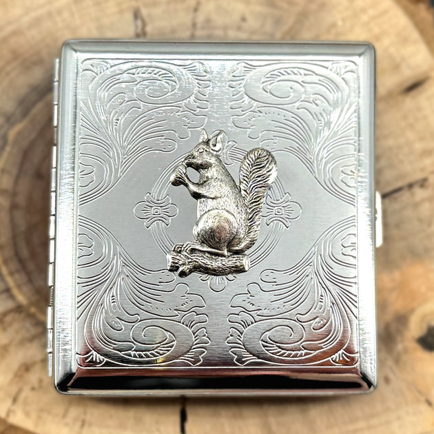 Silver metal cigarette case with raised squirrel design and ornate scrollwork