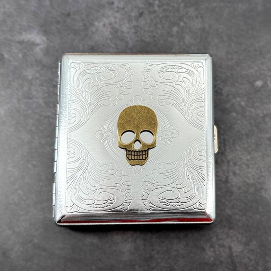 Antique bronze skull metal cigarette case with silver scrollwork background
