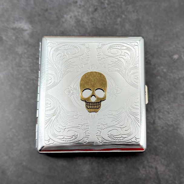 Antique bronze skull metal cigarette case with silver scrollwork background