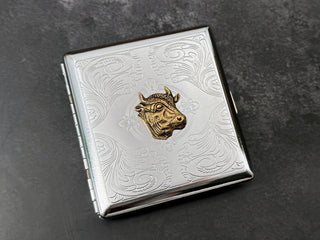 Bronze cow head card holder with intricate floral scrollwork detailing.