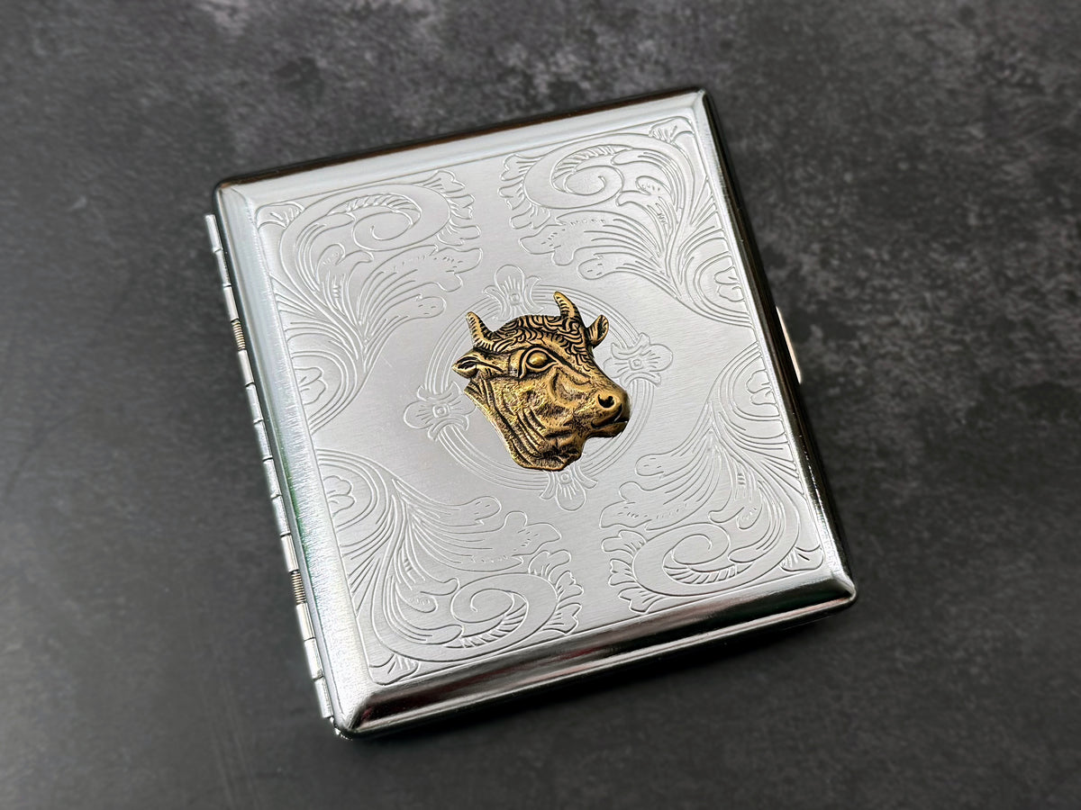 Bronze cow head card holder with intricate floral scrollwork detailing.
