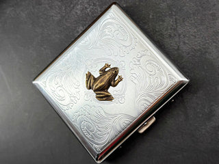 Bronze frog card holder featuring decorative floral scrollwork on a silver case.