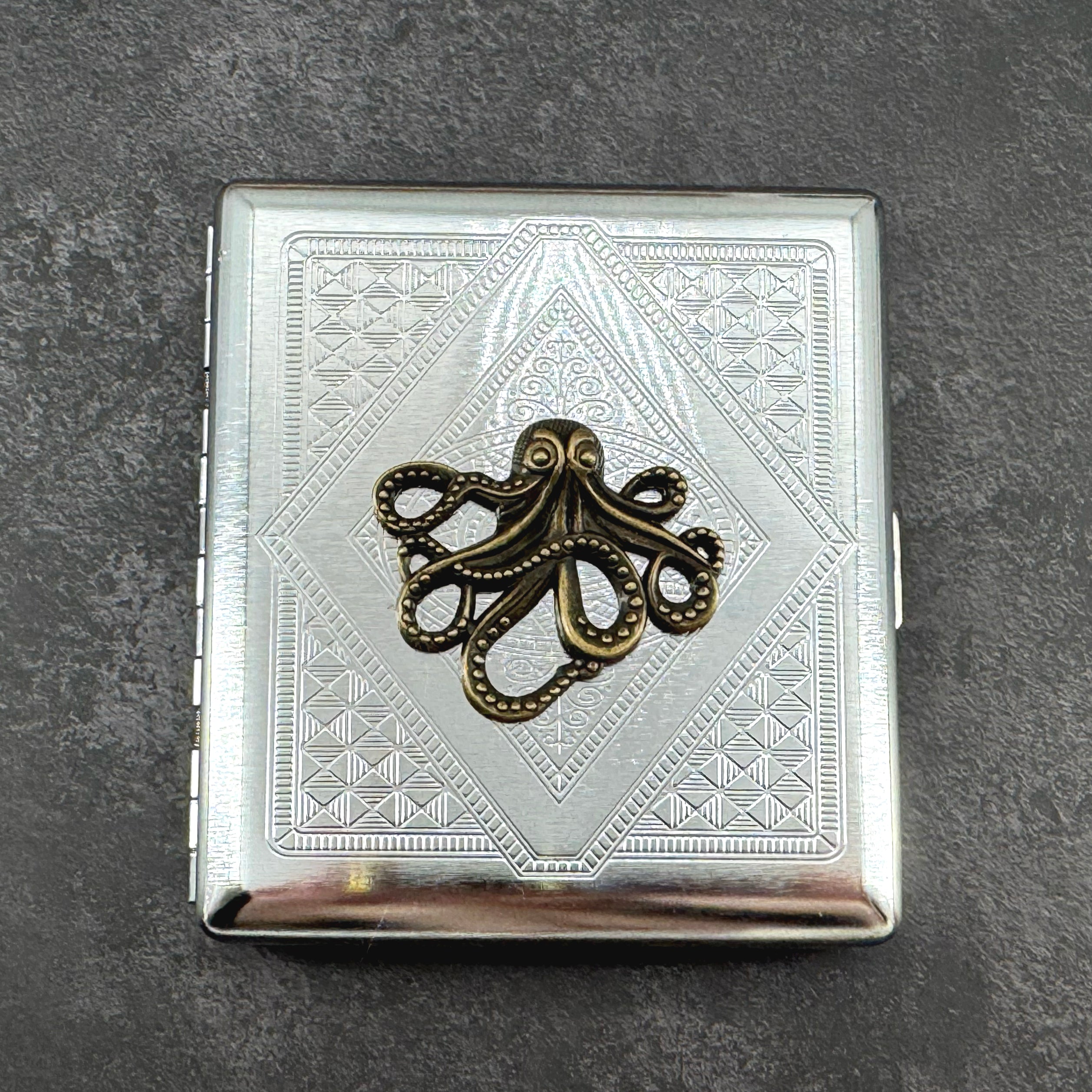 Ink and Tide octopus cigarette case with raised bronze octopus on silver stamped metal background