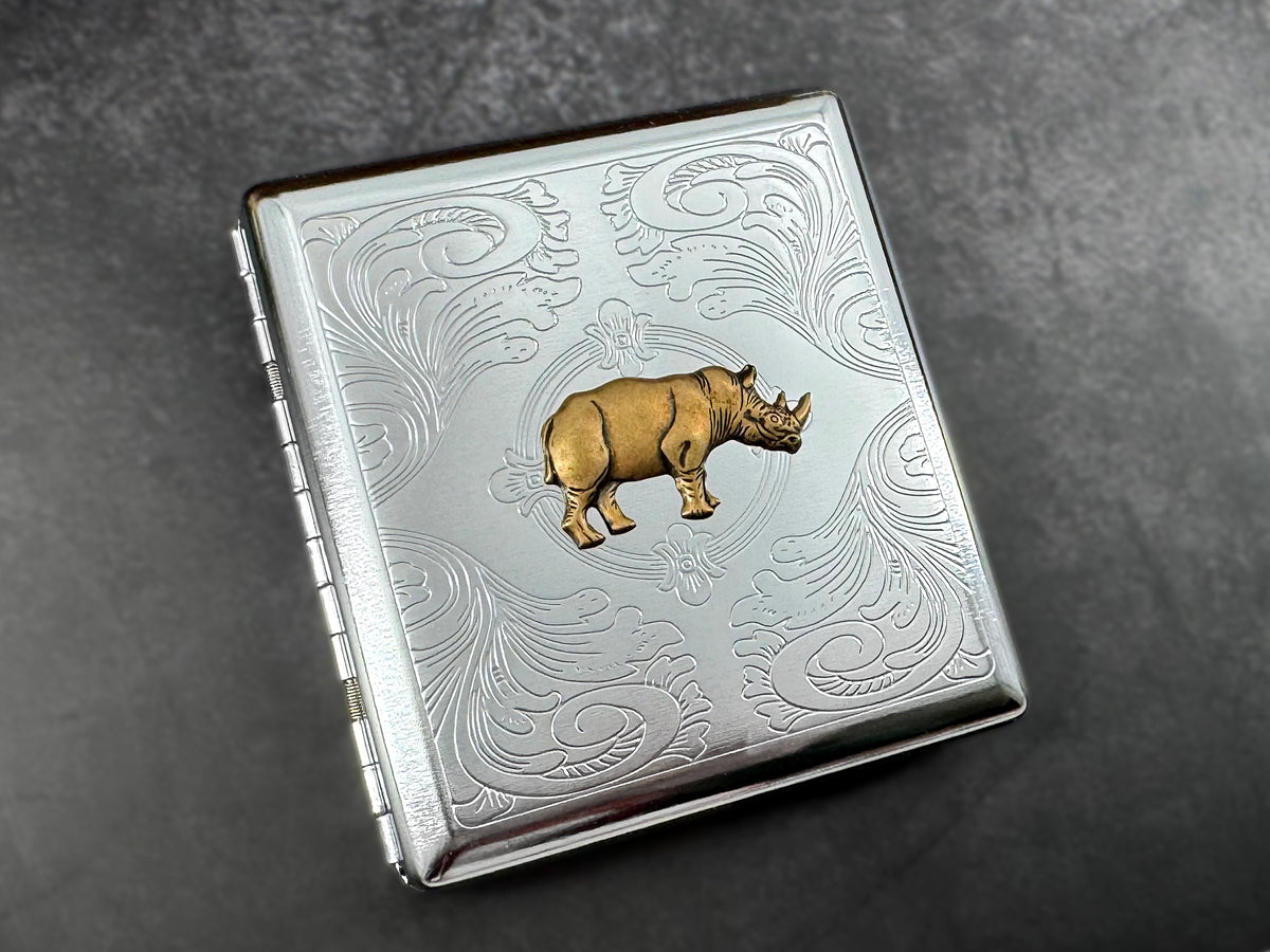 Bronze rhinoceros card holder with decorative floral scrollwork on silver metal.