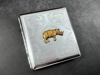Bronze rhinoceros card holder with decorative floral scrollwork on silver metal.