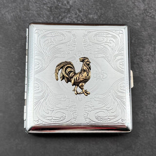 Front view of rooster cigarette case with decorative stamped silver scrollwork background.