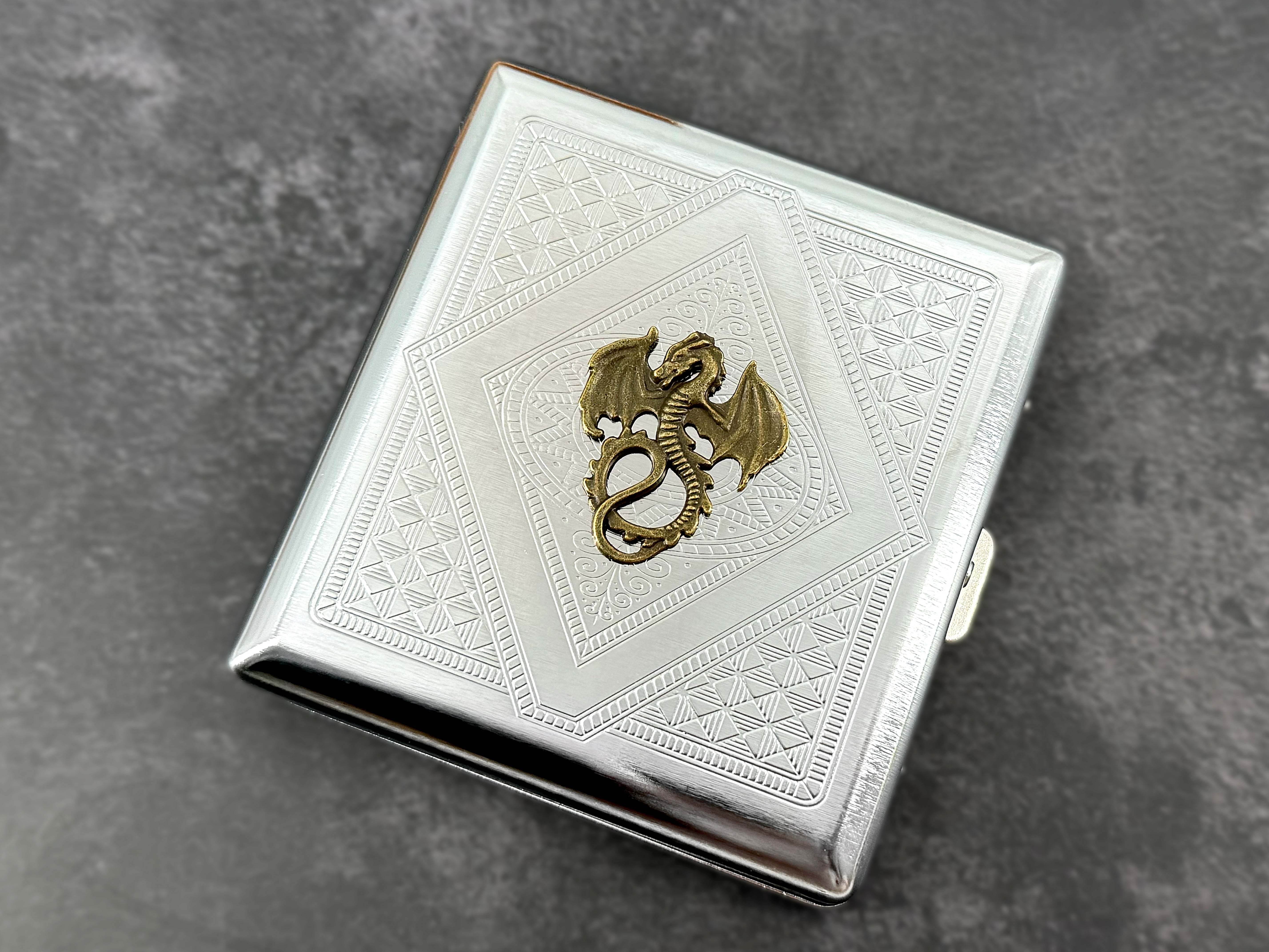 Silver metal cigarette case featuring an antique bronze winged dragon centerpiece