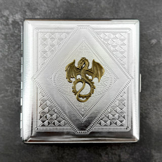 Close-up of antique bronze winged dragon on stamped metal cigarette case