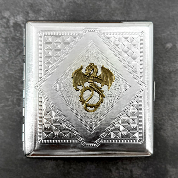 Close-up of antique bronze winged dragon on stamped metal cigarette case