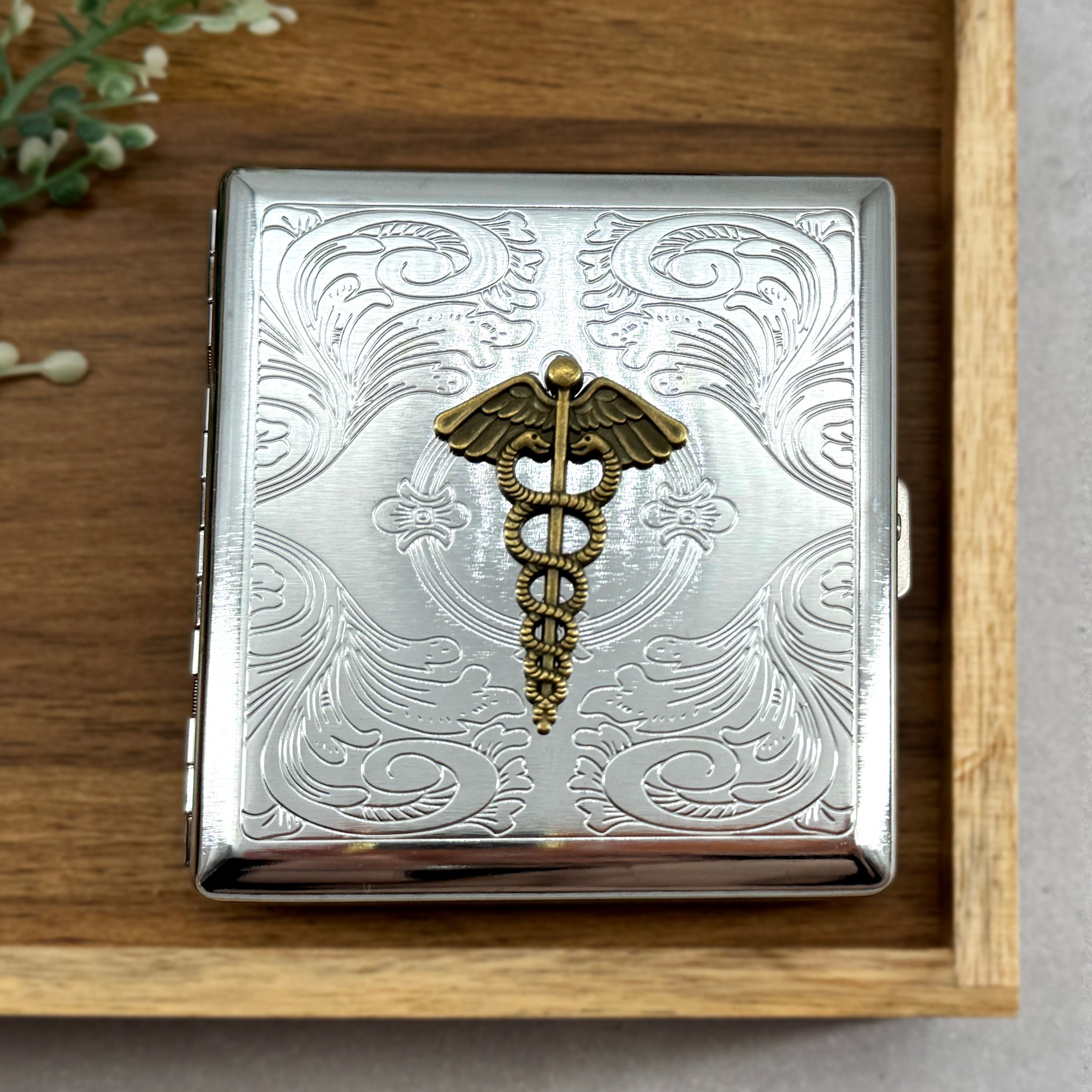 Vintage-inspired caduceus pocket case with ornate engraved background