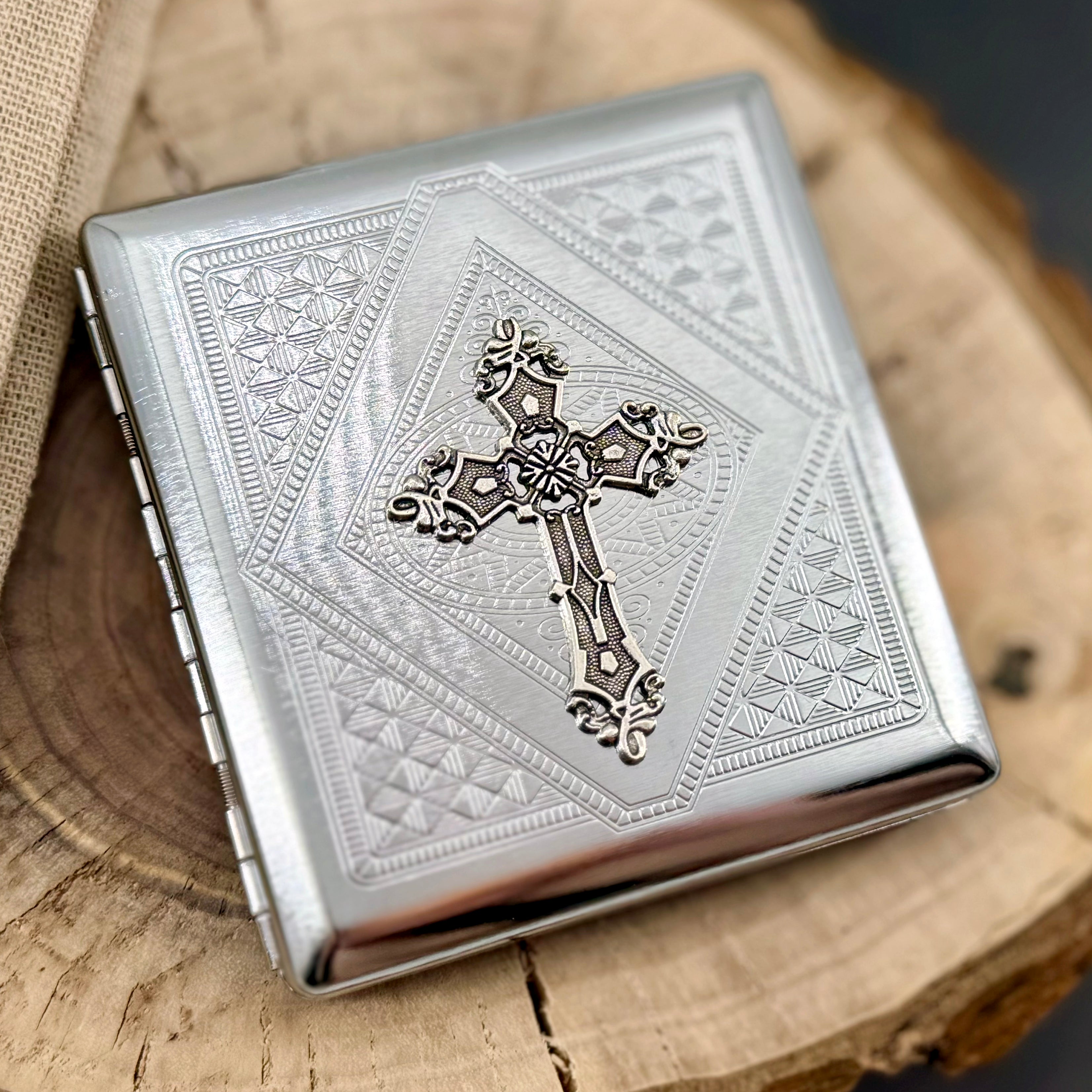 Ornate cross cigarette case with raised cross detail and engraved geometric background