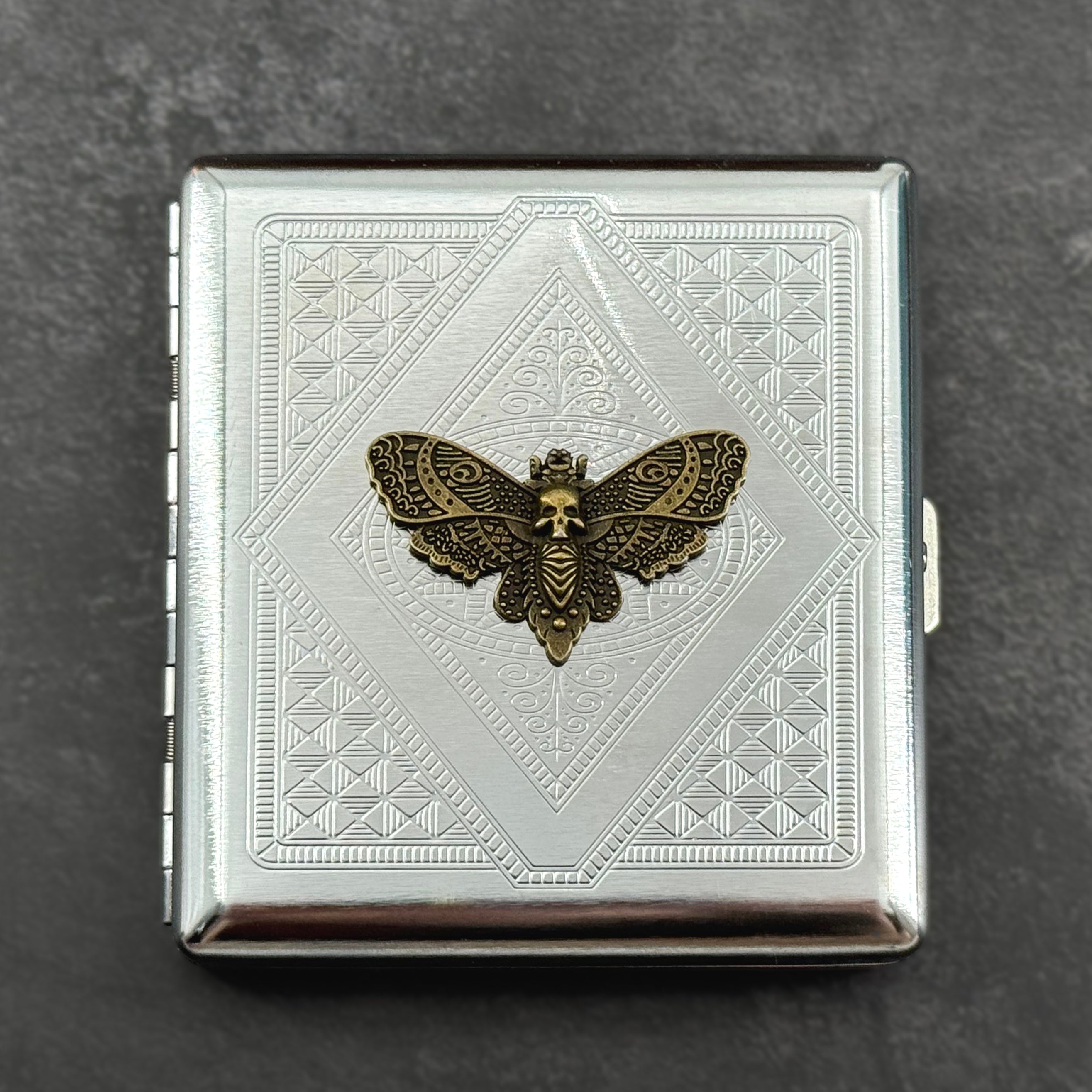 Silver-toned gothic card holder featuring a raised skull moth on an angular geometric pattern