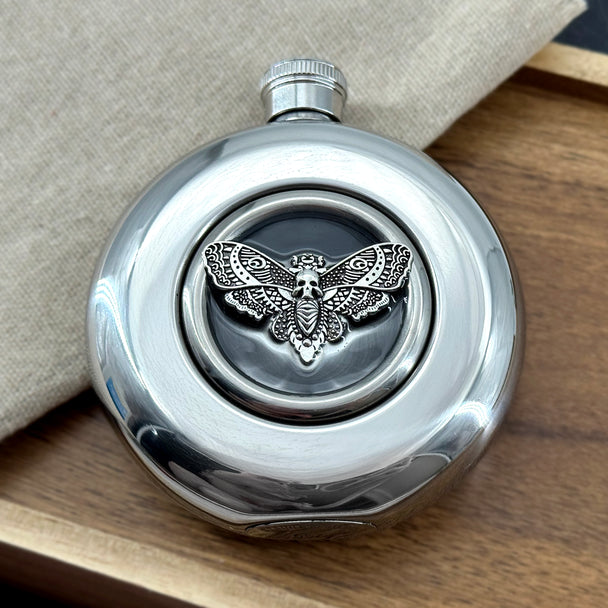 Close-up of silver Death’s-head hawkmoth suspended in clear epoxy resin on a round flask