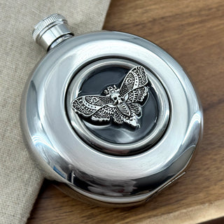 Circular stainless steel hip flask with screw-top lid and clear viewing window