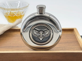 Round stainless steel flask with silver Death’s-head hawkmoth embedded in a clear viewing window
