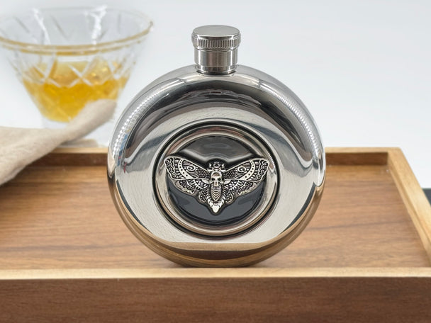 Round stainless steel flask with silver Death’s-head hawkmoth embedded in a clear viewing window