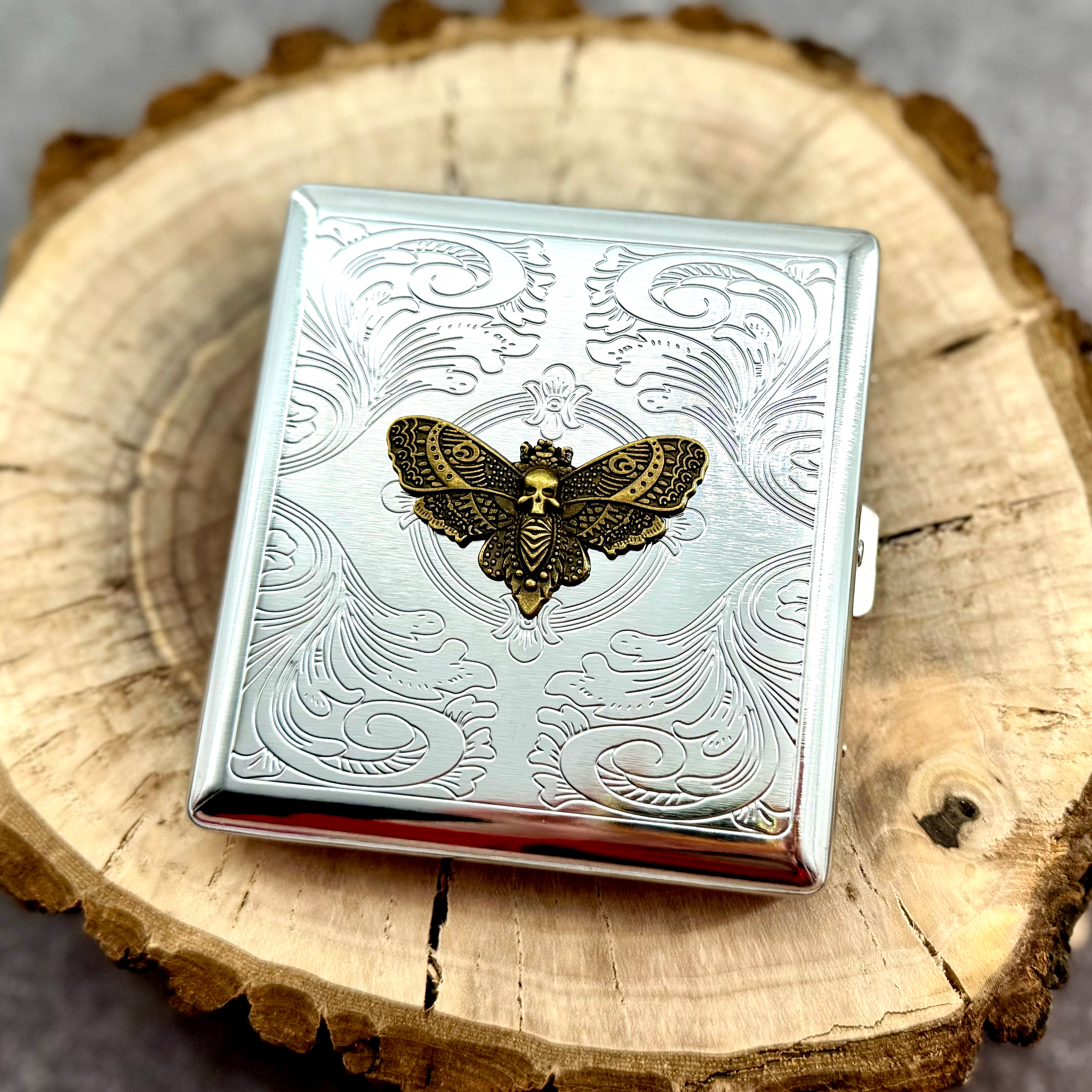 Gothic moth pocket case displayed on a natural wood slice