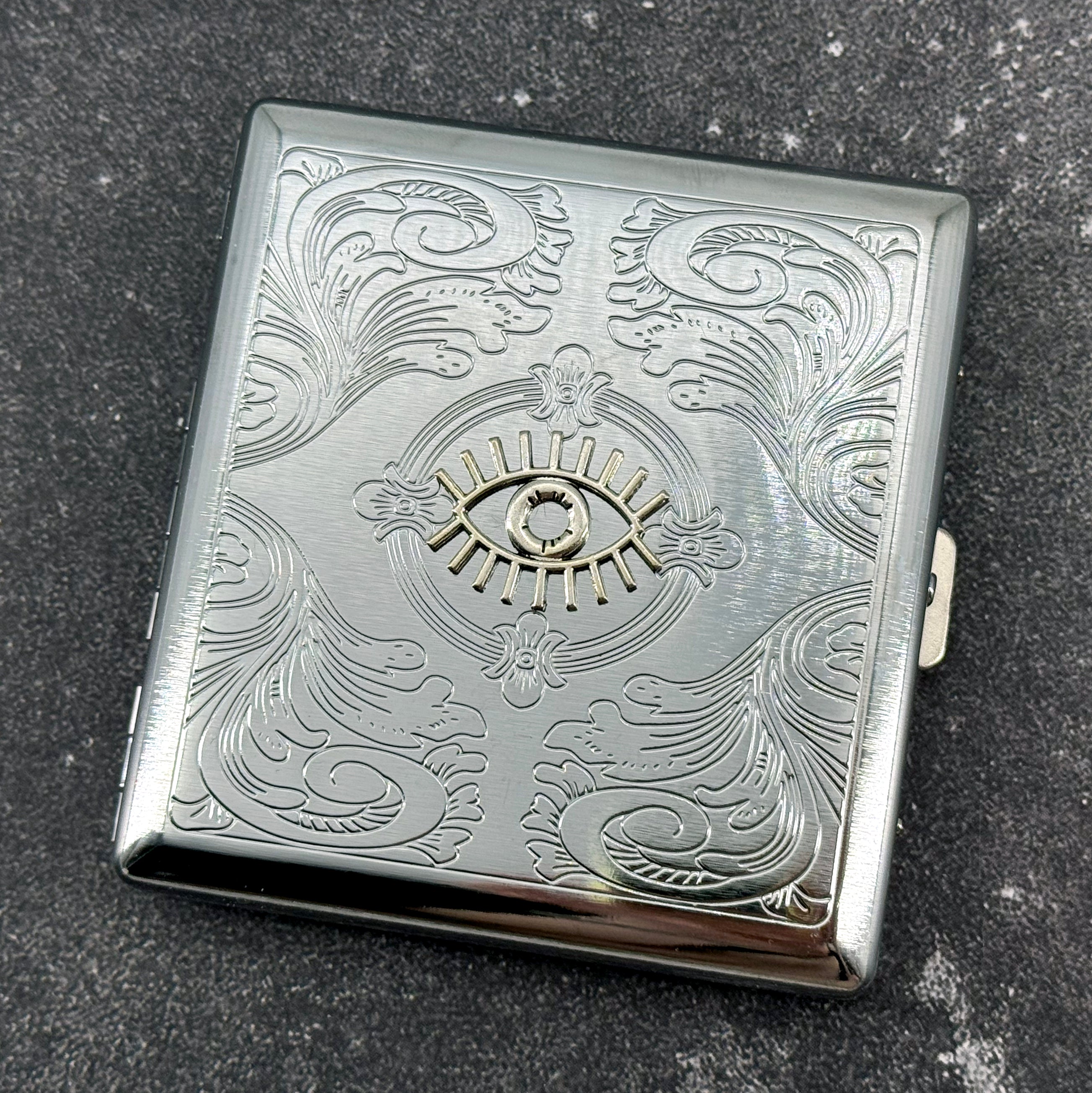 Silver-tone cigarette case with protective evil eye embellishment and secure closure