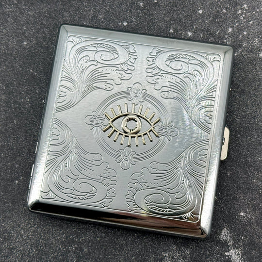 Silver-tone cigarette case with protective evil eye embellishment and secure closure