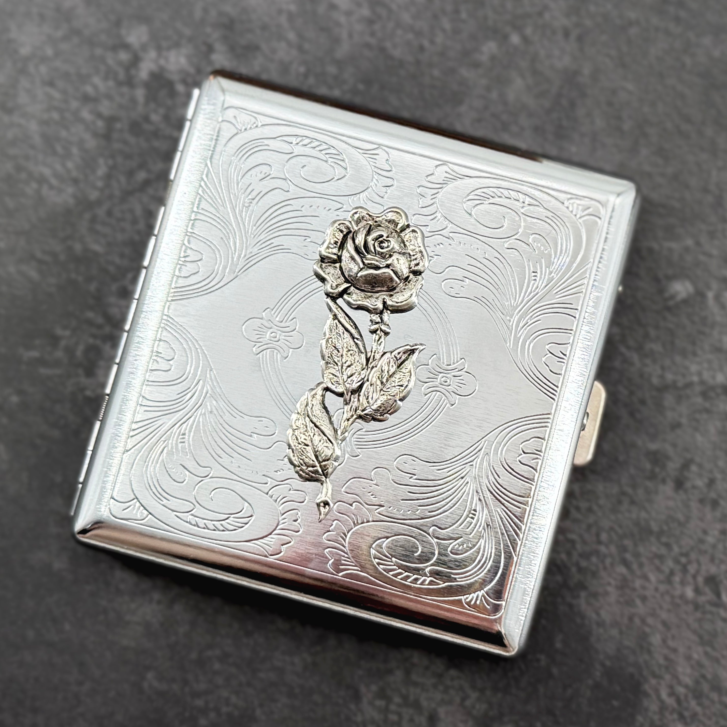 Botanical card holder with detailed silver rose and vintage-inspired floral scrollwork.