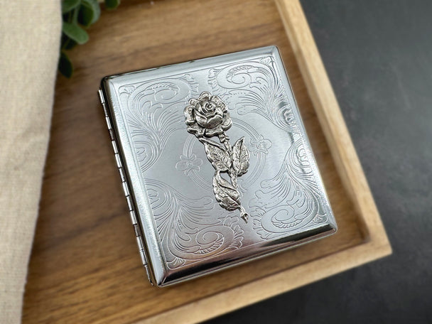 Vintage-inspired floral accessory with raised rose and intricate stamped metal detailing.