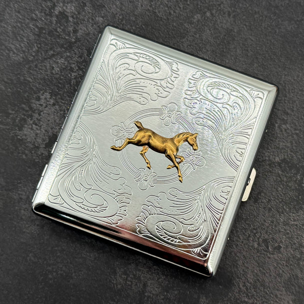 Front view of equestrian metal cigarette case with ornate stamped scrollwork design