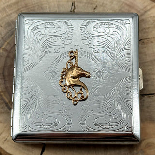 Fantasy-themed metal cigarette case with an ornate stamped metal scrollwork background.
