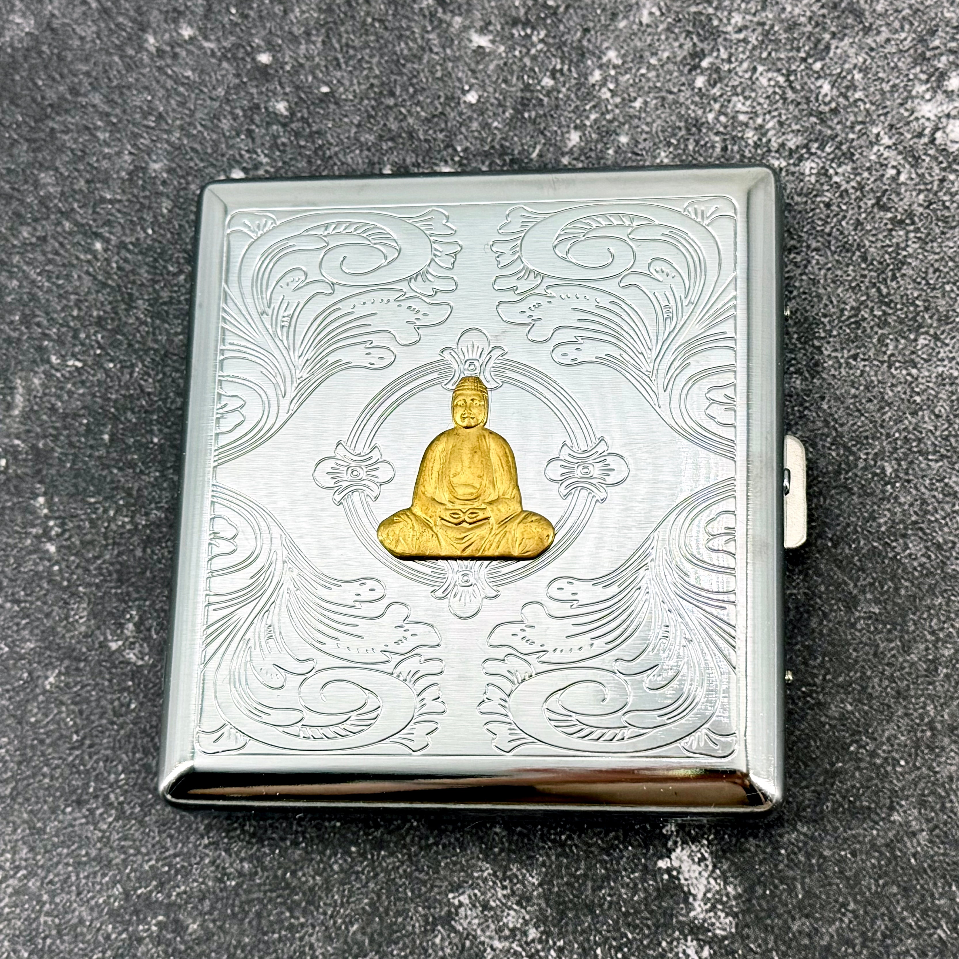 Decorative Buddha cigarette case with raised golden Buddha and engraved ornamental detailing