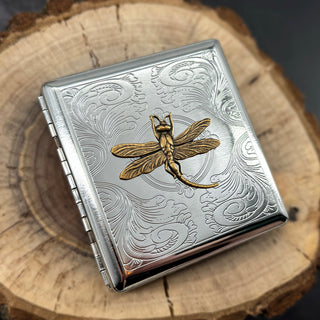 Silver cigarette case featuring a golden dragonfly and decorative floral scroll pattern