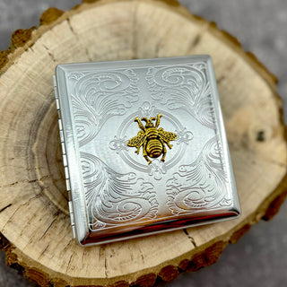 Queen Bee metal pocket case with raised gold bee emblem and stamped scrollwork