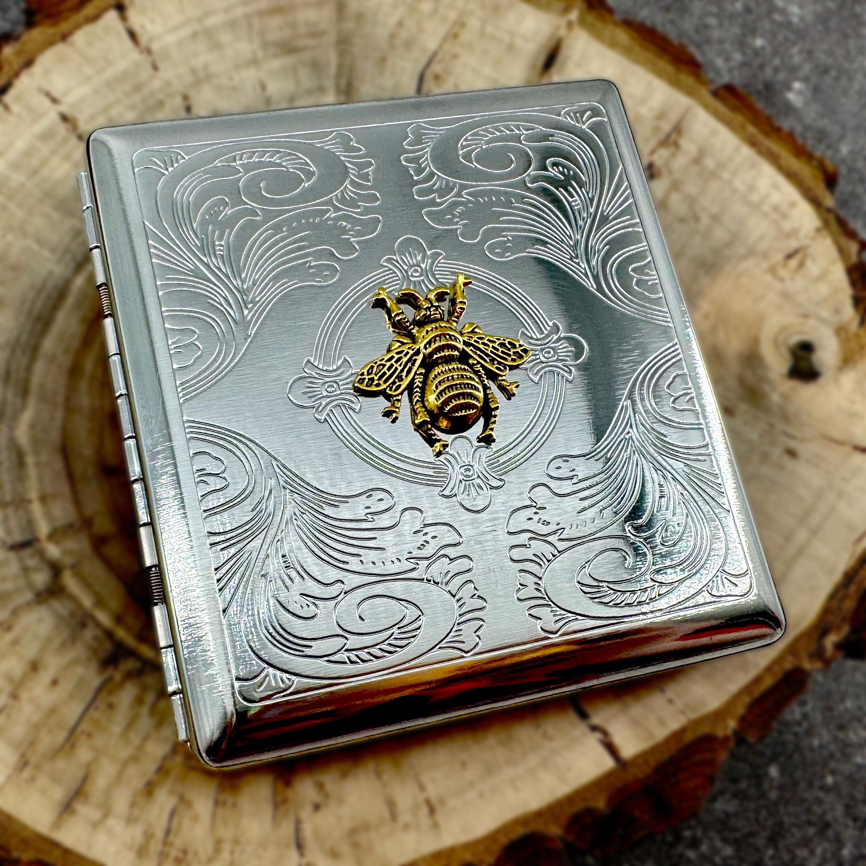 Handmade bee cigarette case displayed on natural wood slice