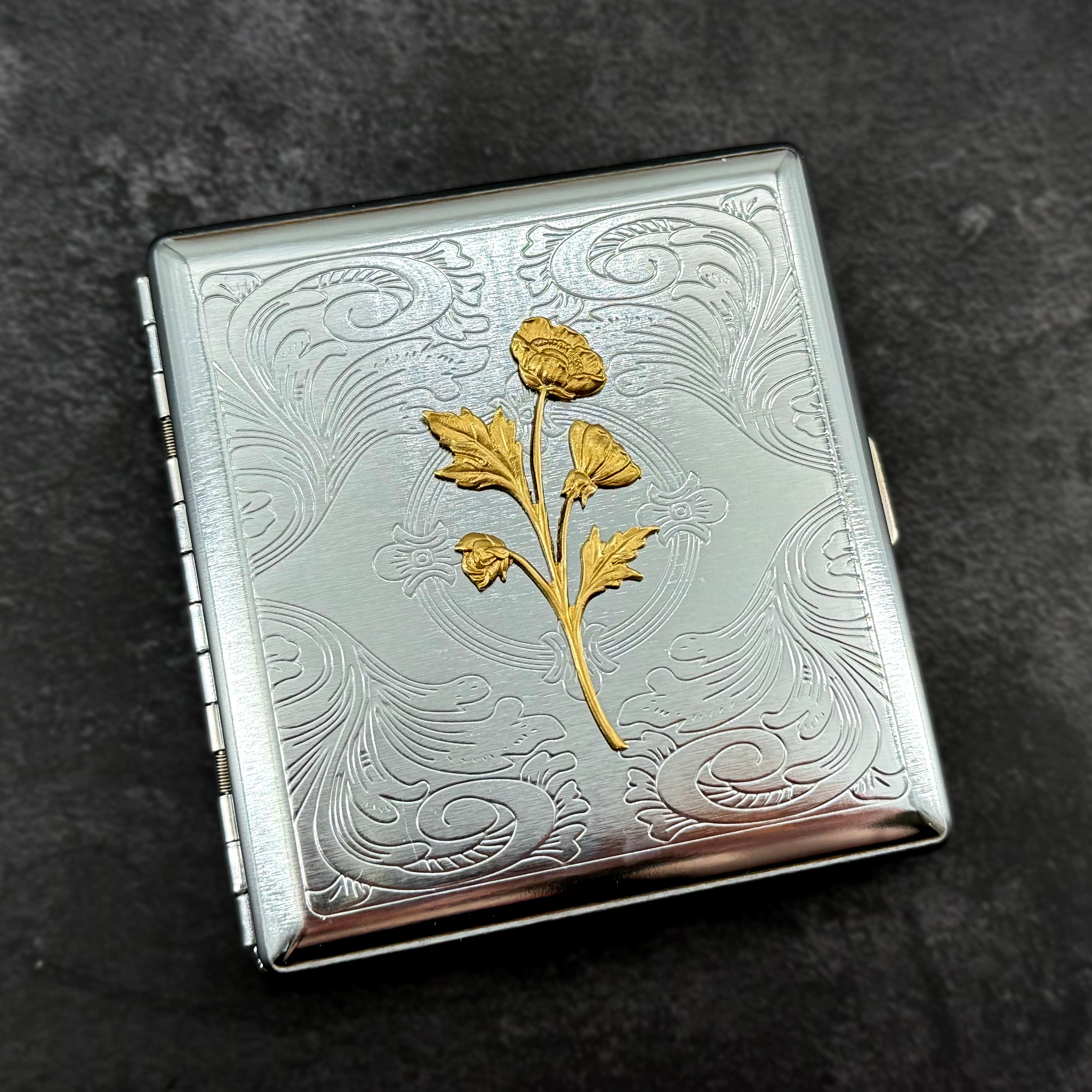 Ornate silver business card holder with raised wildflower decoration.