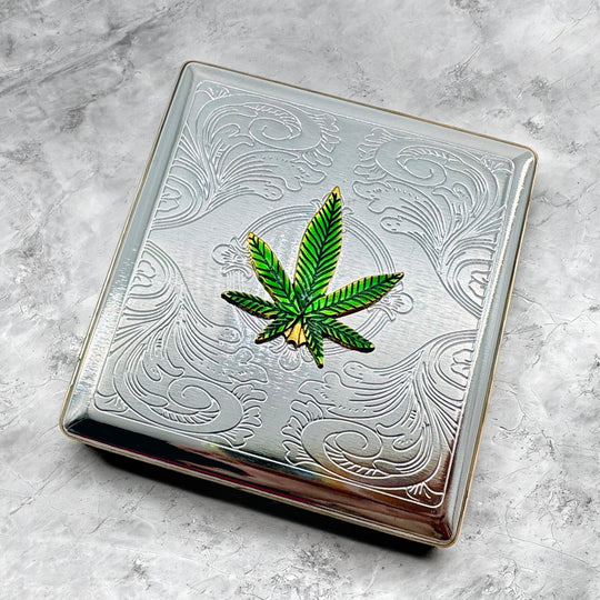 Green cannabis leaf cigarette case displayed on stone background