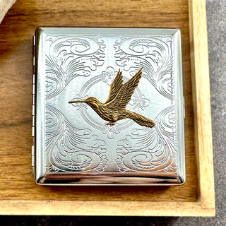Golden hummingbird pocket case displayed on a wooden tray