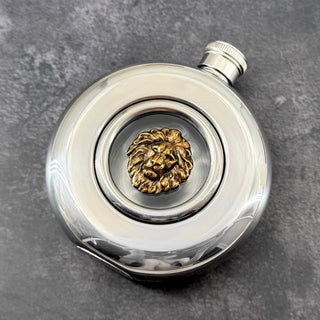 Regal round window flask featuring an antique bronze-toned lion motif and polished stainless steel body