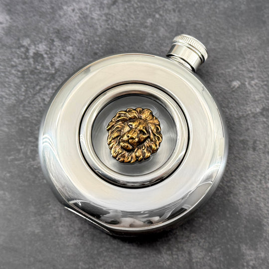 Regal round window flask featuring an antique bronze-toned lion motif and polished stainless steel body