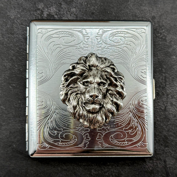 Silver lion cigarette case with decorative stamped metal background and secure snap closure