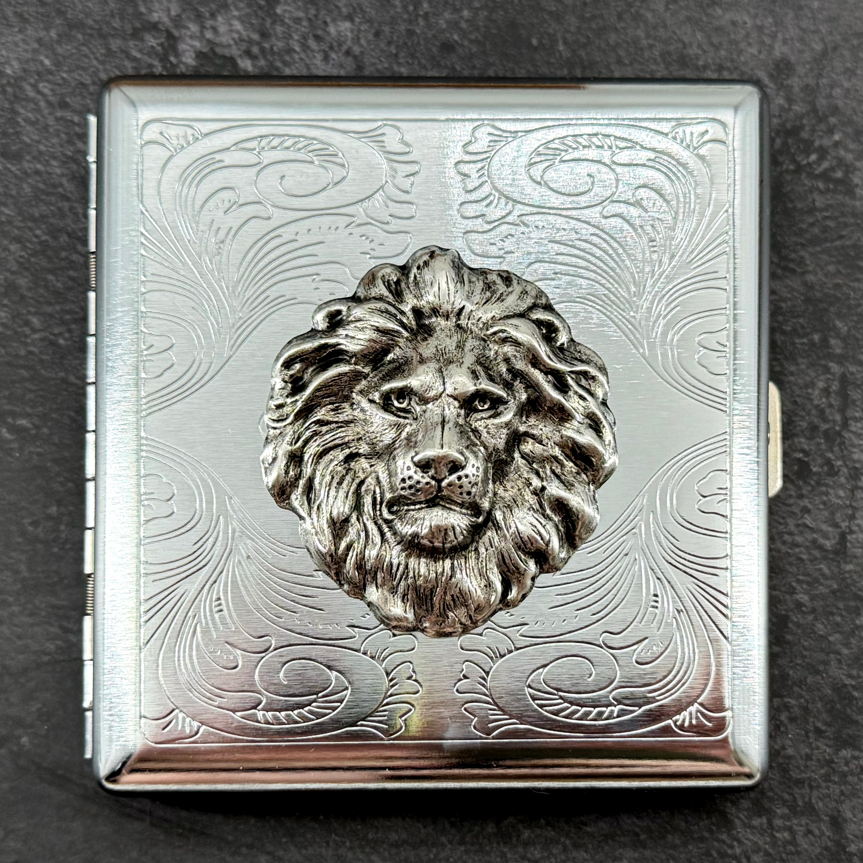 1. Lion head metal cigarette case with raised silver lion and ornate stamped scrollwork