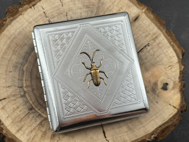 Natural history metal card case with a raised longhorn beetle and decorative geometric stamping