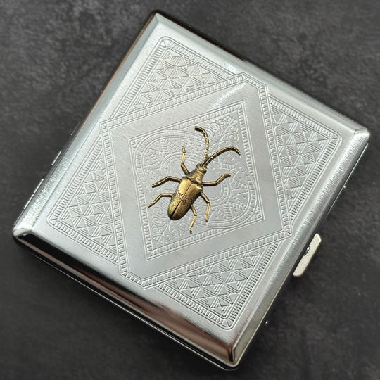 Close-up of the bronze longhorn beetle embellishment on a handcrafted silver metal case