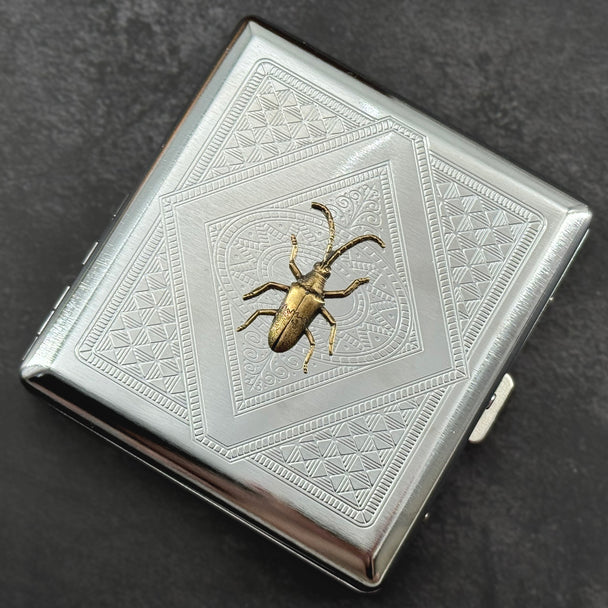 Close-up of the bronze longhorn beetle embellishment on a handcrafted silver metal case