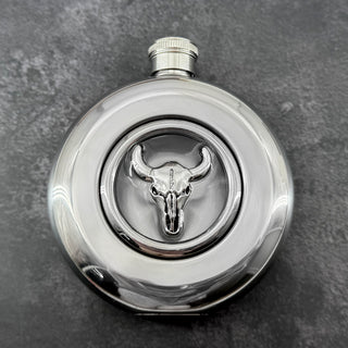 Round window hip flask showing screw-top lid and raised cattle skull design
