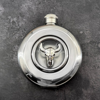 Round stainless steel flask with raised silver longhorn skull and clear circular viewing window