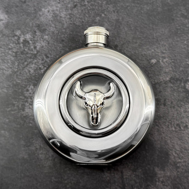 Round stainless steel flask with raised silver longhorn skull and clear circular viewing window