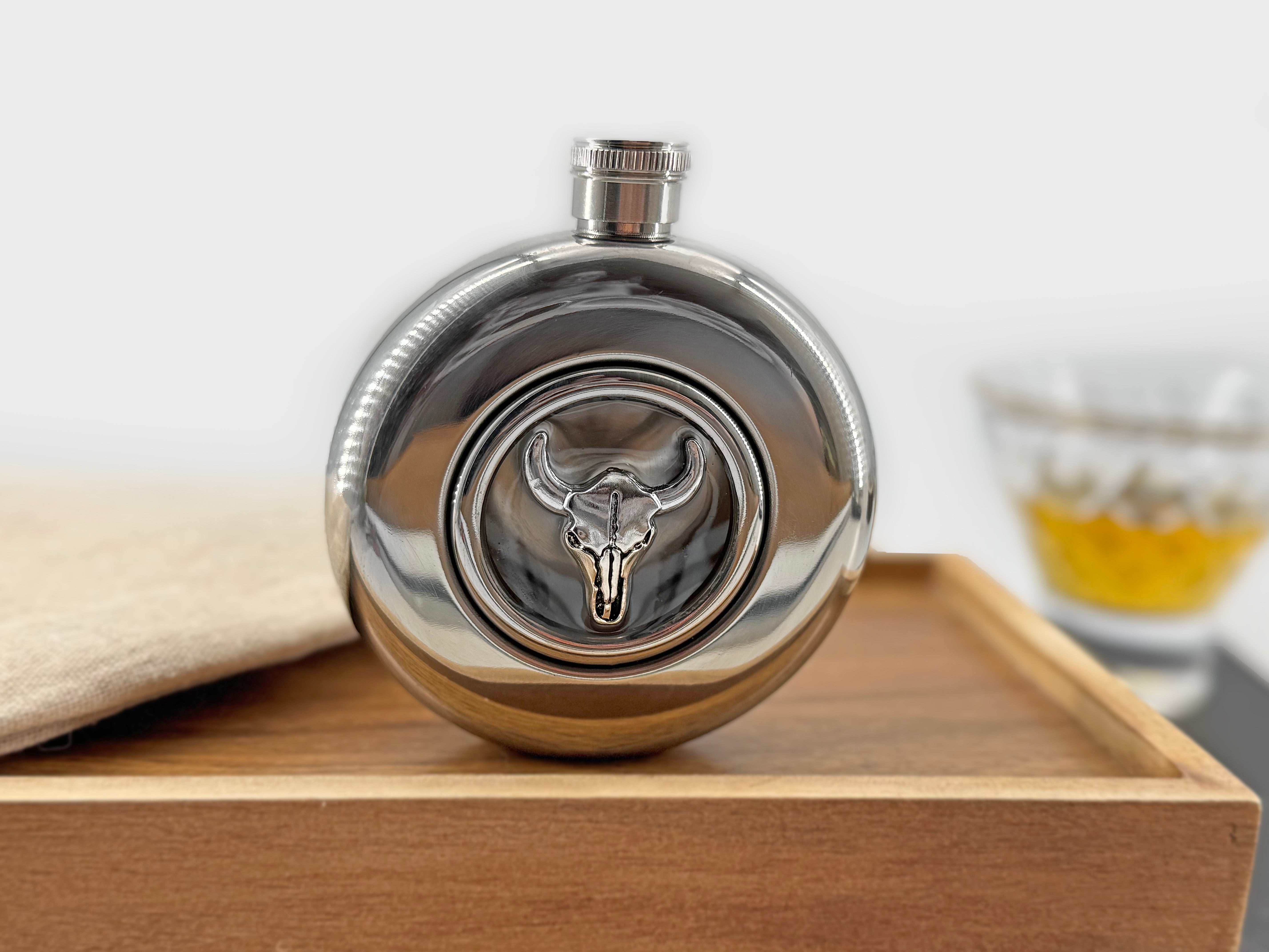 Longhorn skull flask photographed on a wooden tray with whiskey glass in the background