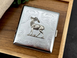 Bull elk metal cigarette case featuring a raised elk on an ornate stamped scrollwork background