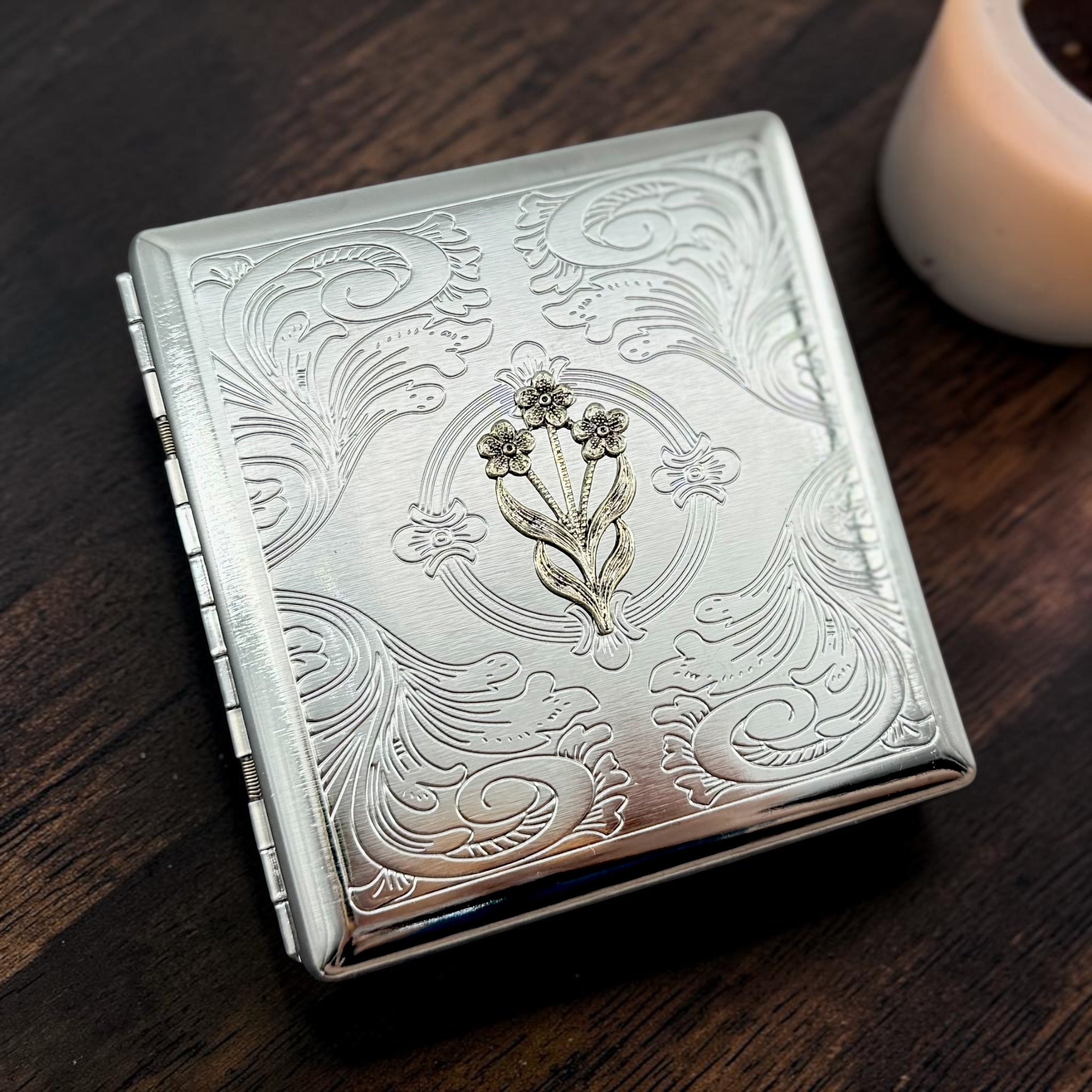 Handmade Petal & Vine cigarette case featuring raised floral design with engraved ornamental background