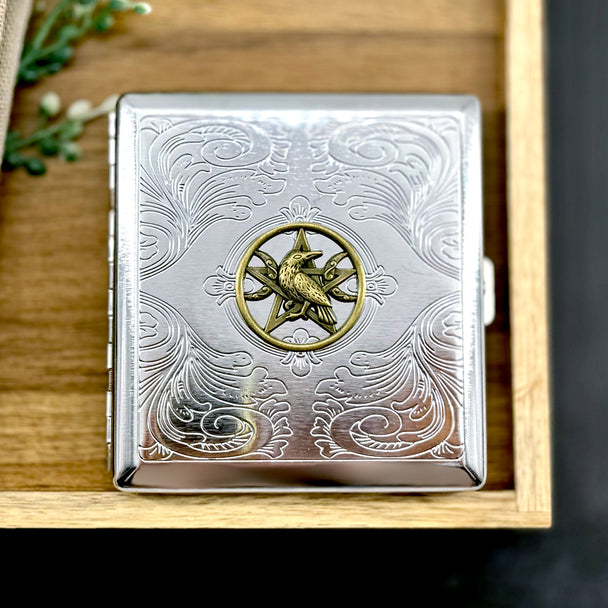 Raven pentacle cigarette case with raised raven emblem and engraved ornamental background