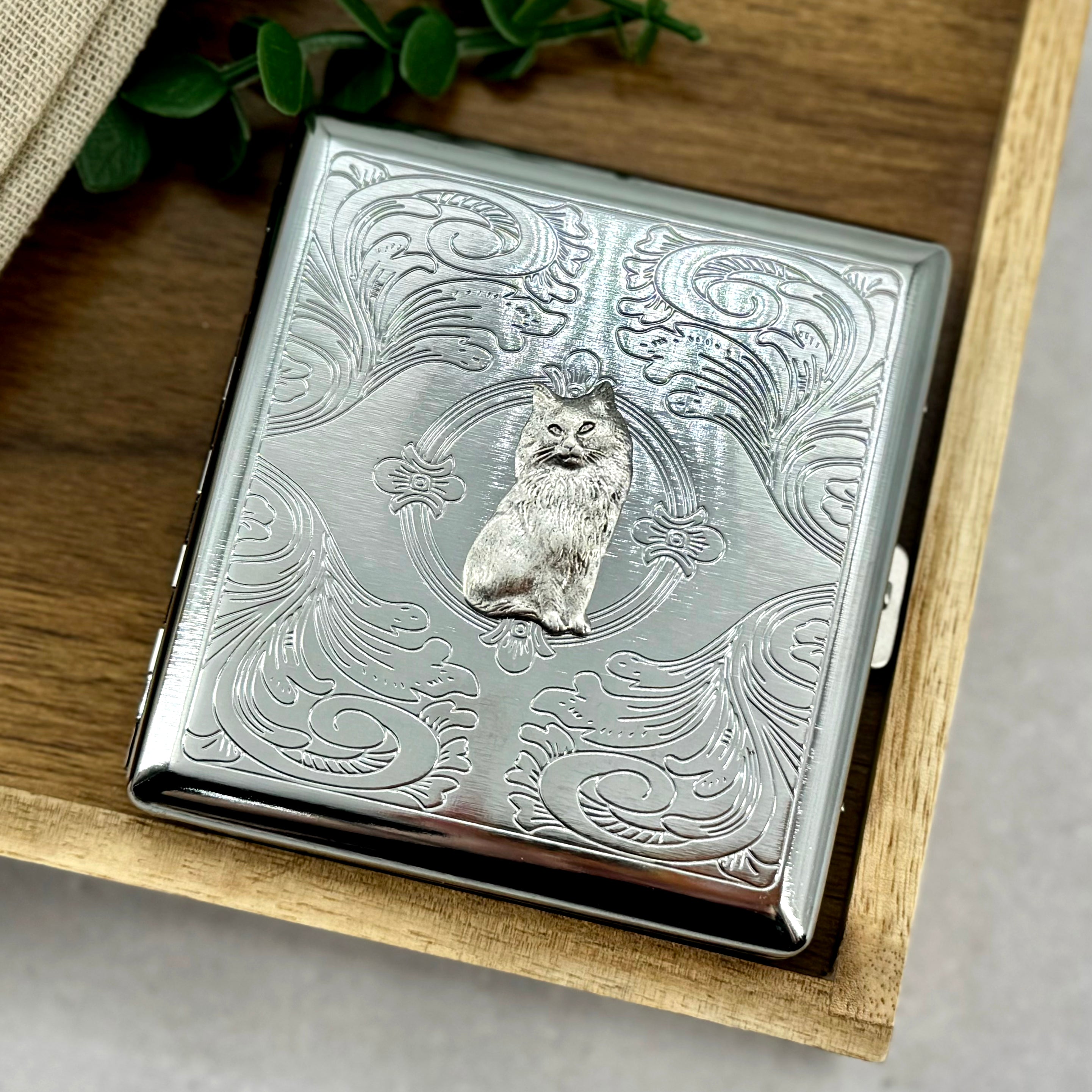 Cat cigarette case displayed in styled product photo showing compact size