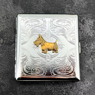 Angled view of Scottie dog metal cigarette case with ornate stamped scrollwork background